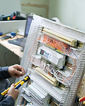 Technician assembling low voltage industrial HVAC control box in workshop. Close-up photo.