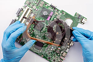 Technician in blue gloves cleaning a laptop fan