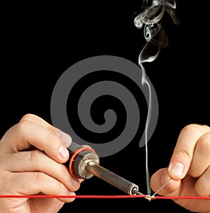 Technician bonding two wires with a solder joint.