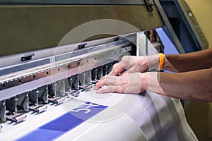 Technician catching a vinyl paper on large inkjet printer