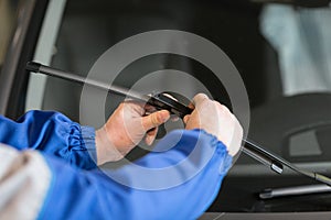 Technician is changing windscreen wipers on a car station.