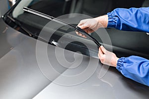 Technician is changing windscreen wipers on a car station.