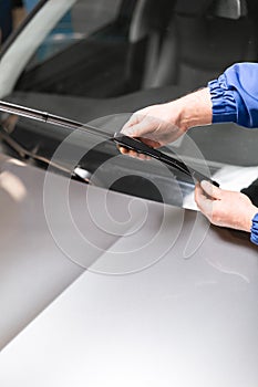 Technician is changing windscreen wipers on a car station.