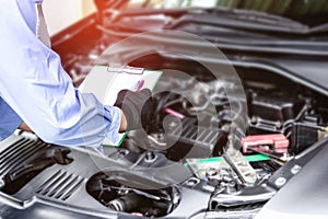 Technician check list problem of car in white paper with engine room service concept