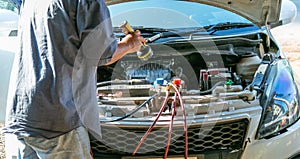 Technician checking air conditioner in engine room of eco car , cleaning air conditioner of car