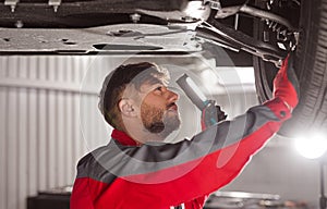 Technician checking car chassis in workshop