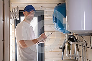 The technician checking the heating system in the boiler room writing down the readings in a notebook