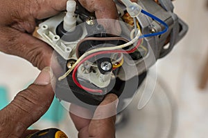 A technician checks a defective capacitor of an old oscillating electric fan