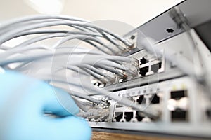 Technician checks the quality of internet connection against background cable hub close-up