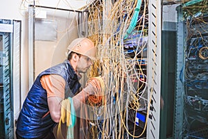 A technician commutes many trouble-free wires in the data center server room. Engineer repair broken internet connection. A