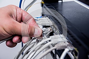 Technician connecting network cables to switches. Connecting cables