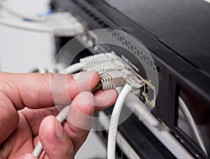Technician connecting network cables to switches. Connecting cables