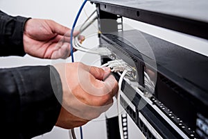 Technician connecting network cables to switches. Connecting cables