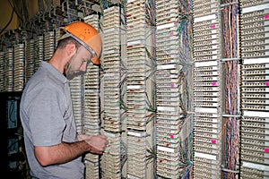 The technician connects the wires to the patch panel of the server room of the data center. The engineer works with the telephone