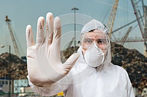 Technician in coverall showing hand as stop gesture