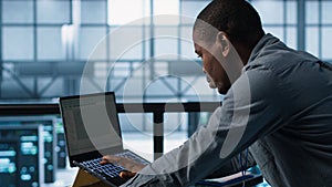 Technician in data center using programming languages on laptop