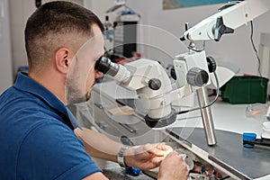 Technician in dental lab working under a microscope