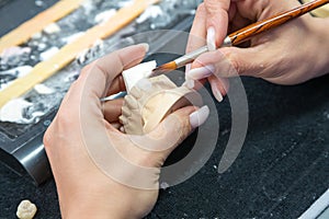 Technician in a dental laboratory applying ceramics to a prosthesis