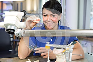 Technician in a dental laboratory presenting a prosthesis into the camera