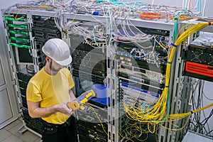 A technician diagnoses a problem area in a telecommunication network. The engineer in a white helmet measures the level of the