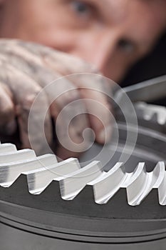 Technician with dirty hand rasping a gear wheel