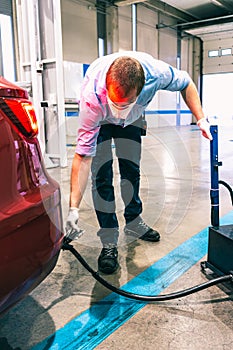 A technician doing an emission control of a security inspection of a vehicle protected with a mask and gloves to prevent the