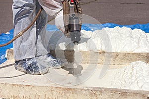 Technician dressed in a protective white uniform spraying foam i
