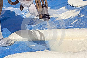 Technician dressed in a protective white uniform spraying foam i