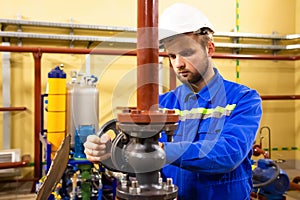 Technician employee opens gate valve on industrial pipeline