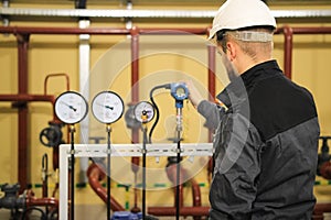 Technician engineer checking pressure sensors manometers and monitoring data on gas industrial station.