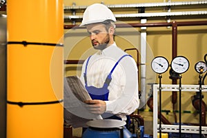 Technician engineer reads drawing on heating boiler station