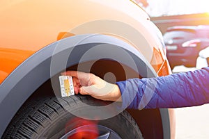 Technician examining the car tire grip with a measuring instrument in service station. Mechanic measures with profiler tread depth