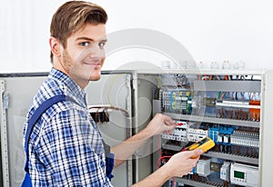 Technician examining fusebox with insulation resistance tester