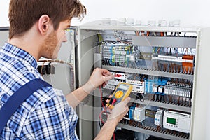 Technician examining fusebox with insulation resistance tester