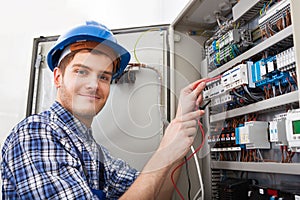 Technician examining fusebox with multimeter probe