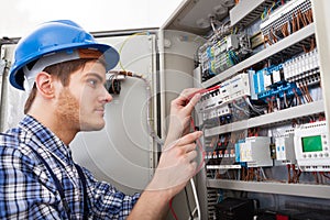 Technician examining fusebox with multimeter probe