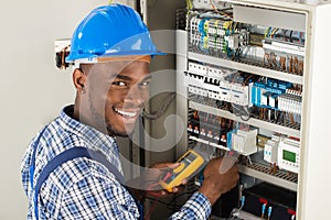 Technician Examining Fusebox With Multimeter Probe photo