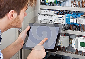 Technician examining fusebox using tablet photo