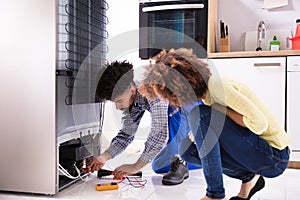 Technician Examining Refrigerator With Digital Multimeter