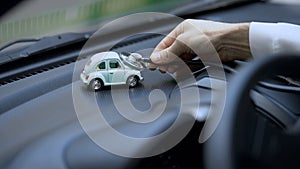 Technician examining toy car with stethoscope, vehicle insurance, maintenance