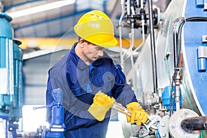 Technician in factory at machine maintenance photo
