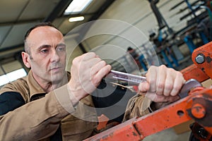 Technician in factory at machine maintenance working with wrench