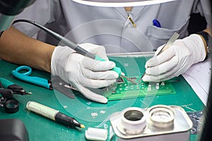Technician female using soldering to weld electronics  circuit board