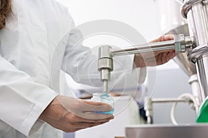 Technician filling container with liquid for laboratory tests