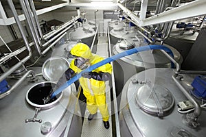 technician filling large silver tank in factory