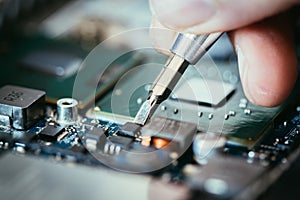 Technician is fixing a computer circuit board, hand and screwdriver