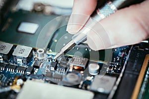 Technician is fixing a computer circuit board, hand and screwdriver