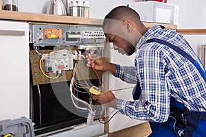 Technician Fixing Dishwasher With Digital Multimeter