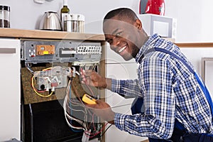 Technician Fixing Dishwasher With Digital Multimeter