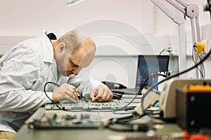 Technician fixing motherboard by soldering
